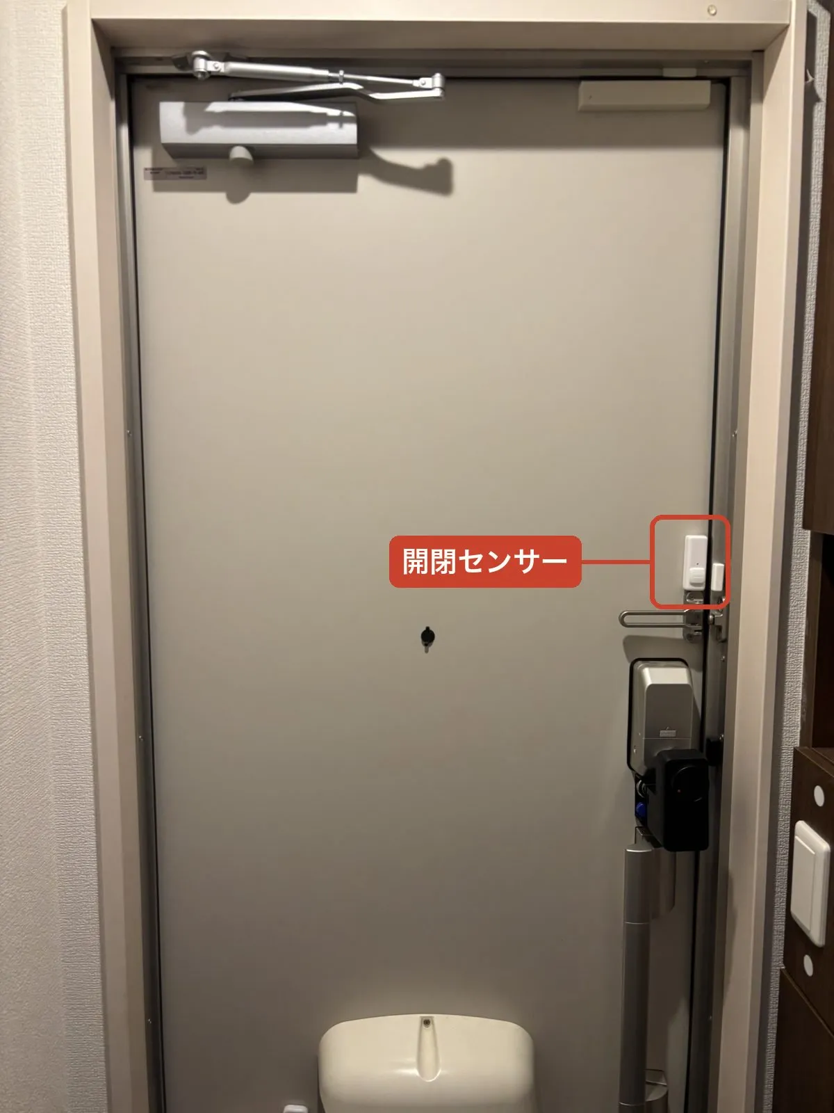 玄関ドア全体で見た開閉センサーの設置位置。朱色の枠の部分が開閉センサー（下はスマートロック）