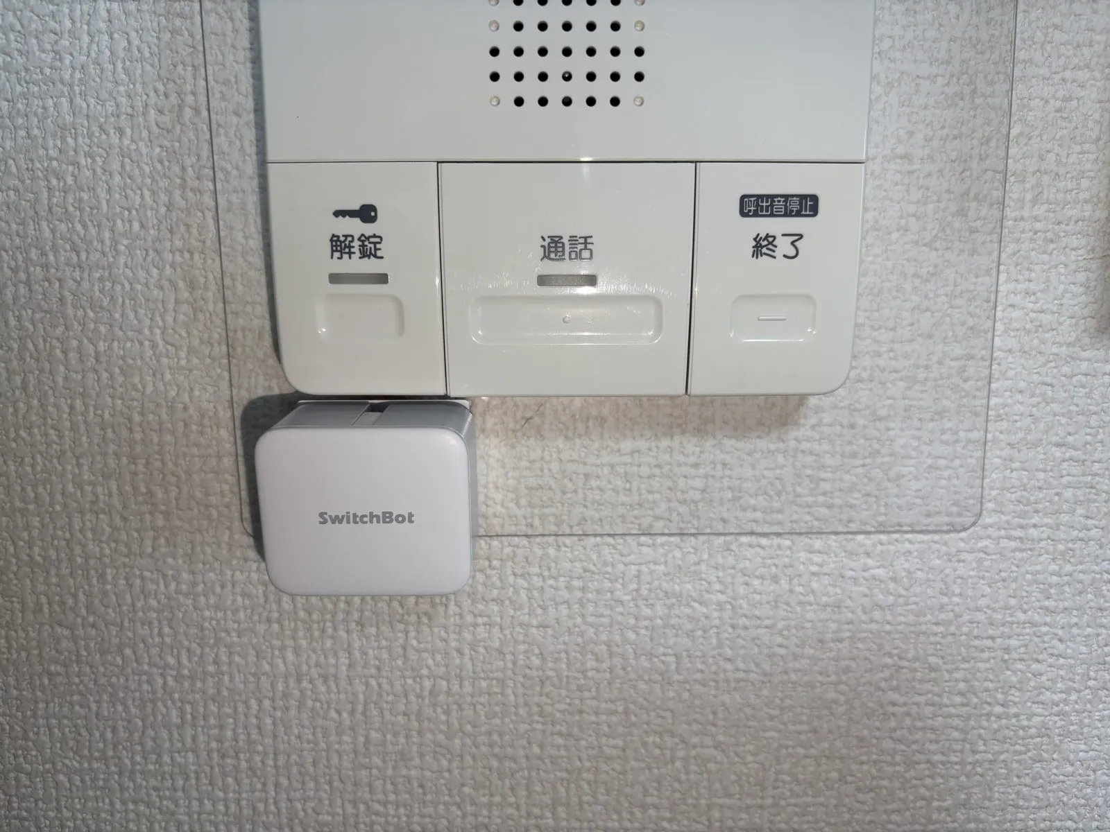 インターホン親機の解錠ボタンのすぐ下に設置したボット（押すモード）